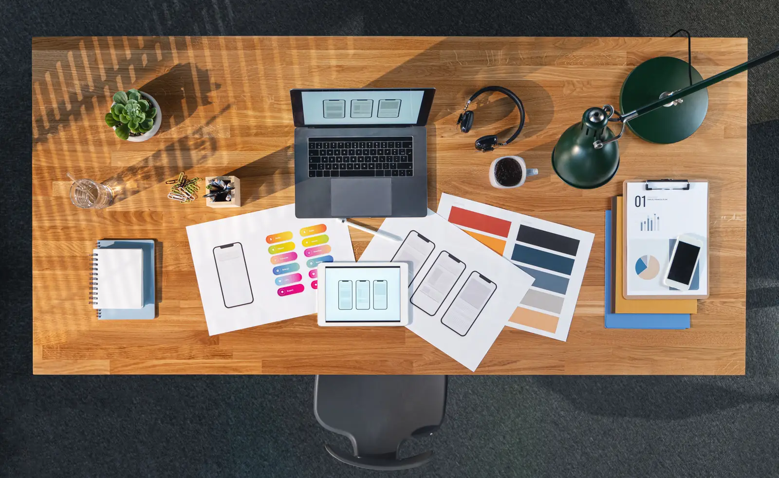 Top view de mesa de trabalho com laptop, tablet e prints de telas de aplicativo — estação de design de produto B2B